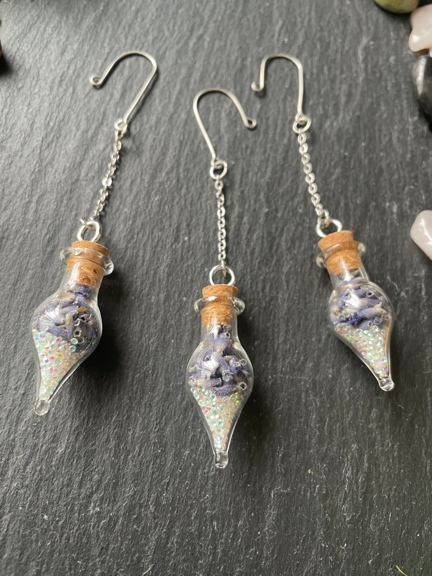 Glass vials filled with lavender and sparkles on a dark surface