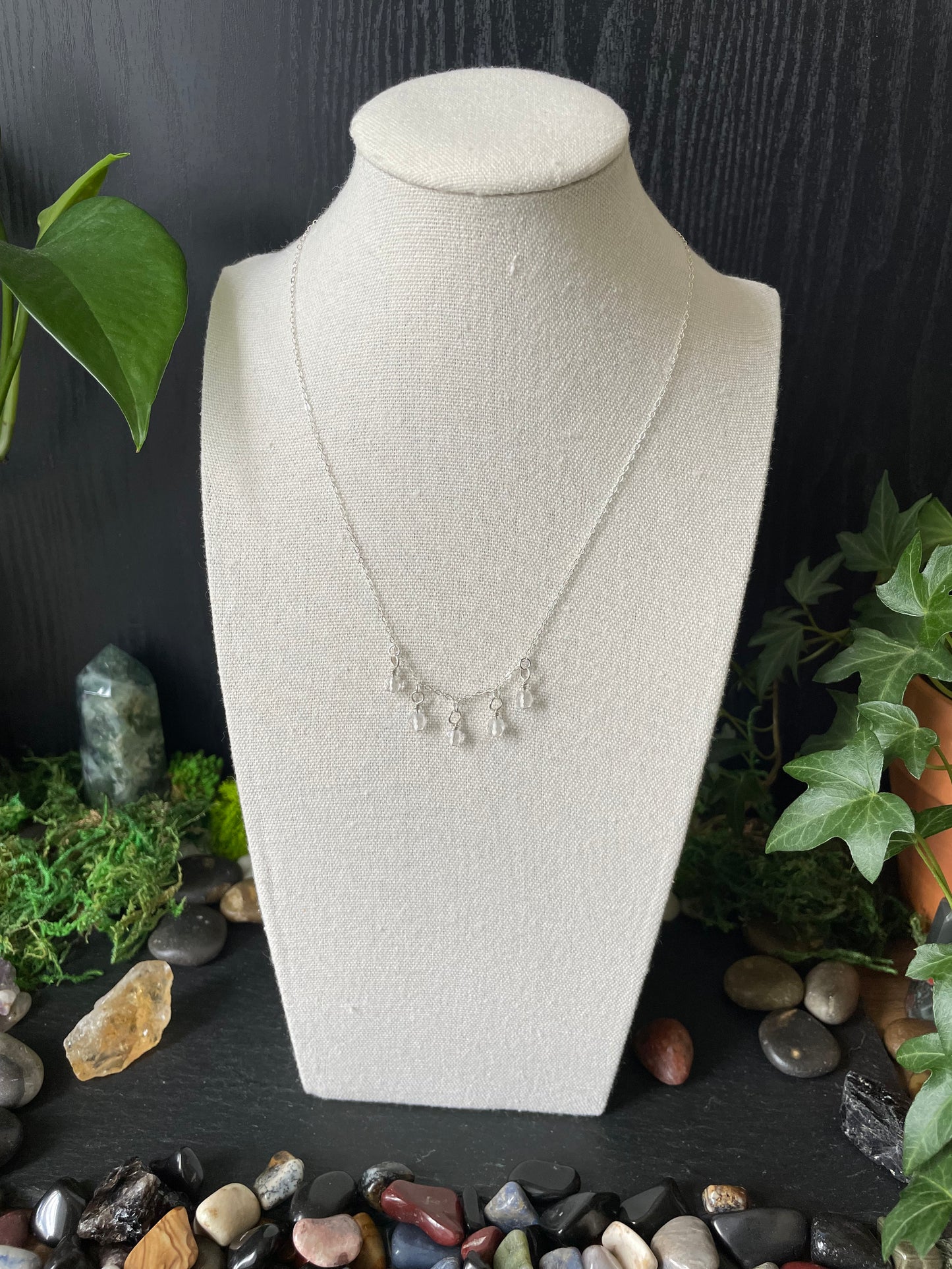 Necklace on a white bust with a natural stone and plant background