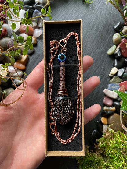 Hand holding a decorative necklace in a box with a natural stone and moss background