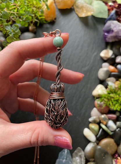 Hand holding a decorative pendant with a natural stone background