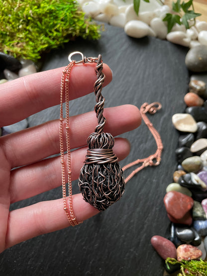 Image of an antiqued copper miniature witch broom pendant with double twisted handle