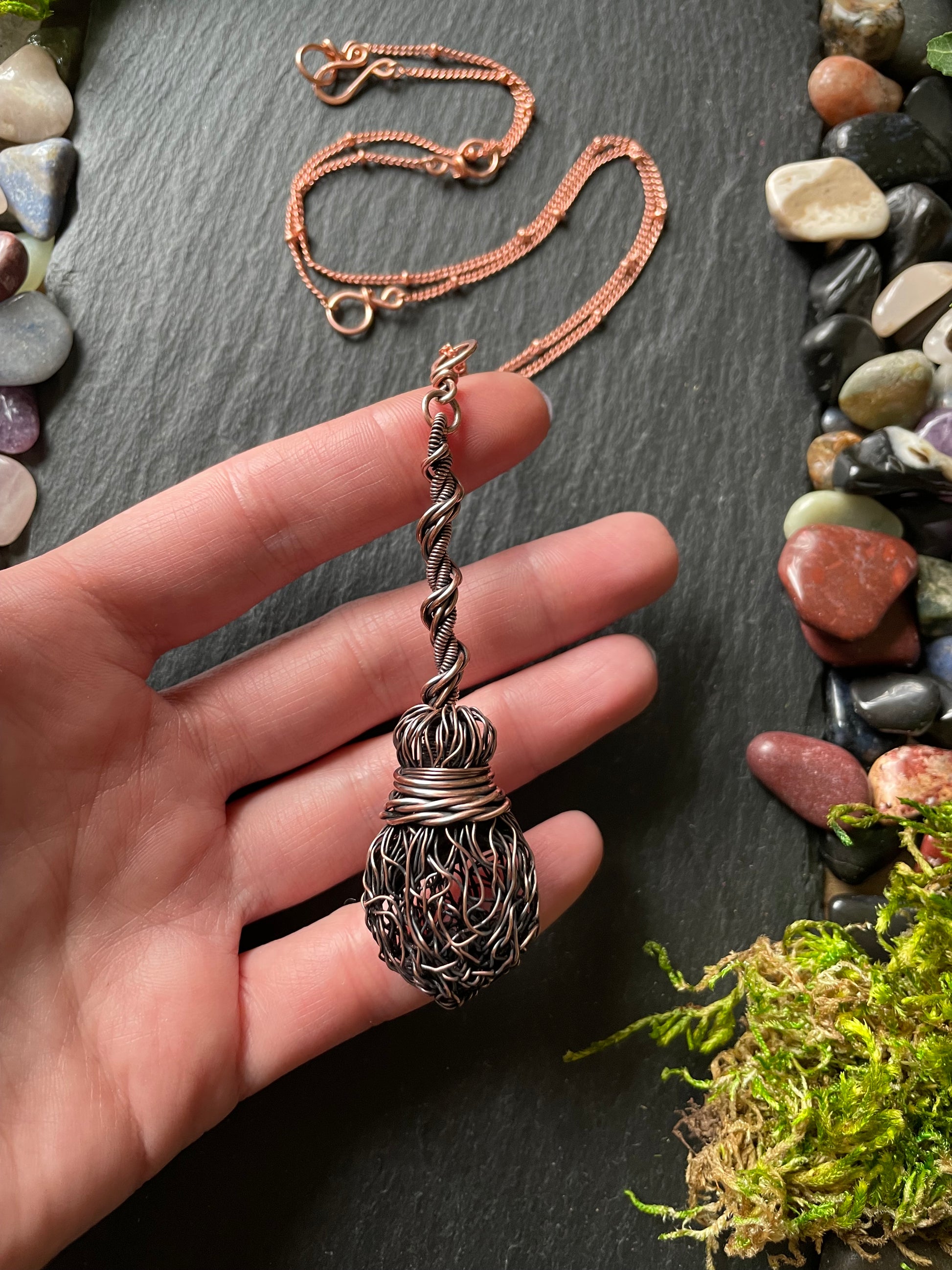 Image of an antiqued copper miniature witch broom pendant with double twisted handle