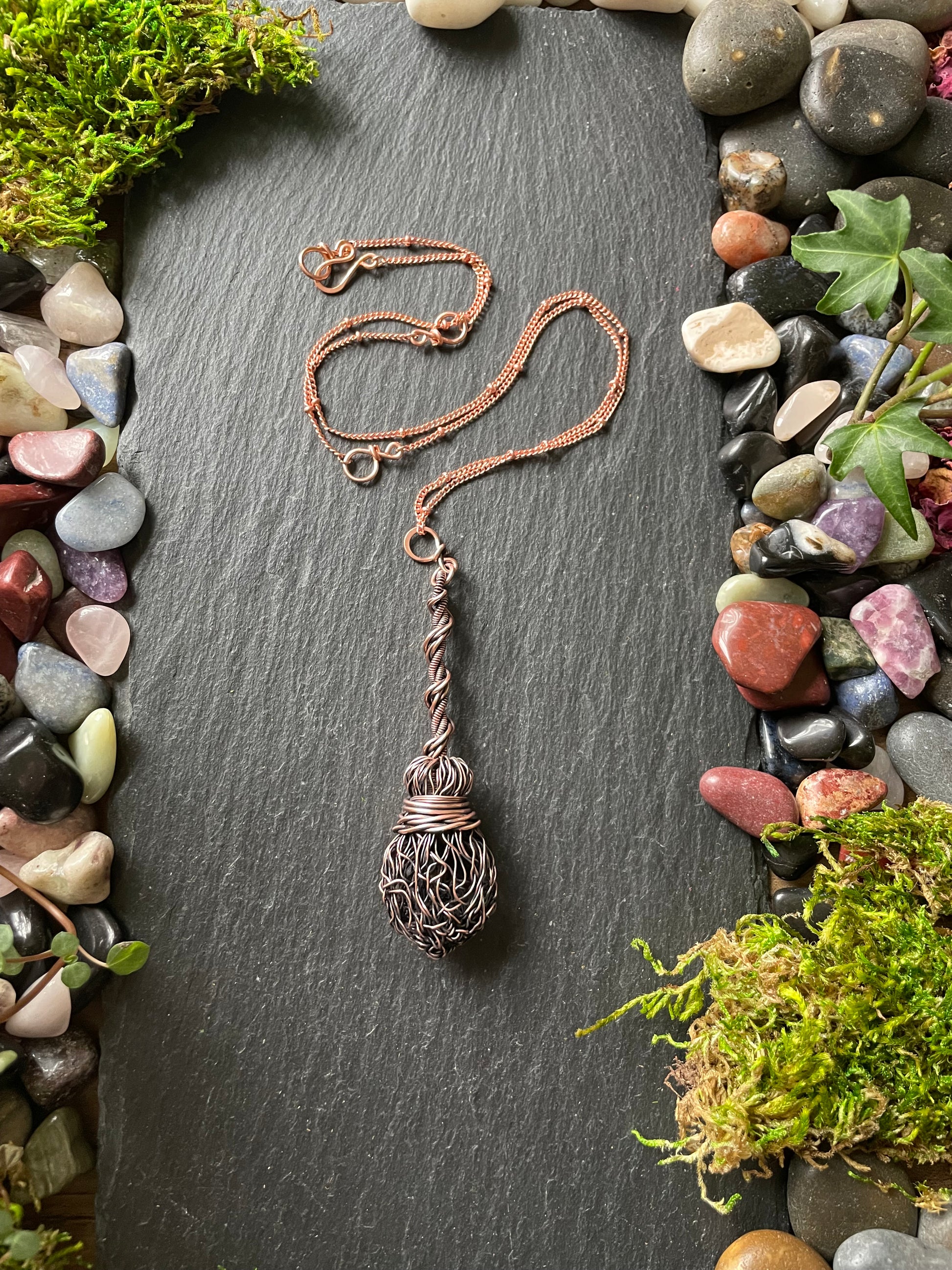 Image of an antiqued copper miniature witch broom pendant with double twisted handle