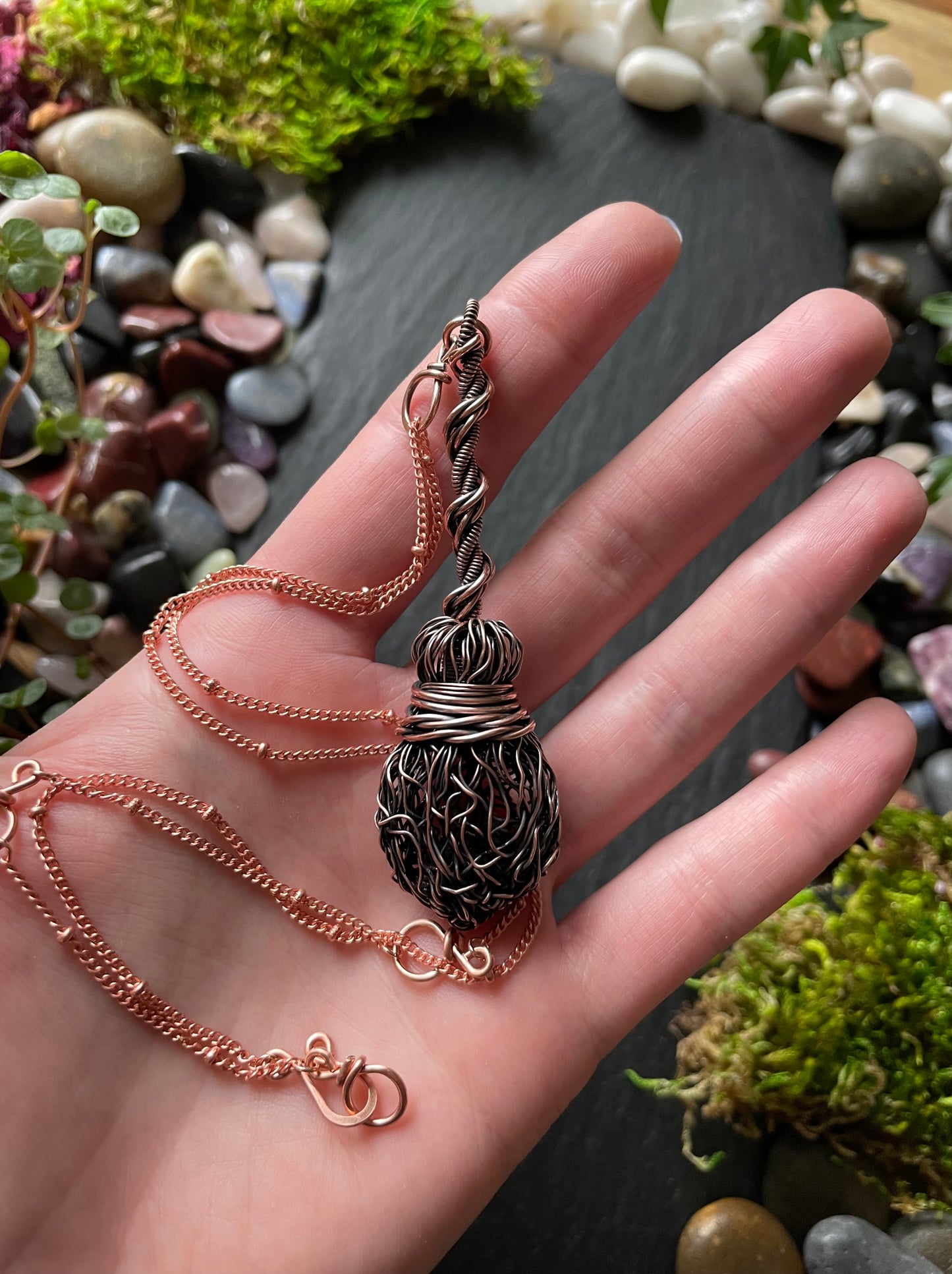 Image of an antiqued copper miniature witch broom pendant with double twisted handle