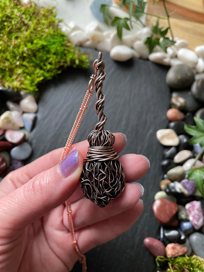 Image of an antiqued copper miniature witch broom pendant with double twisted handle