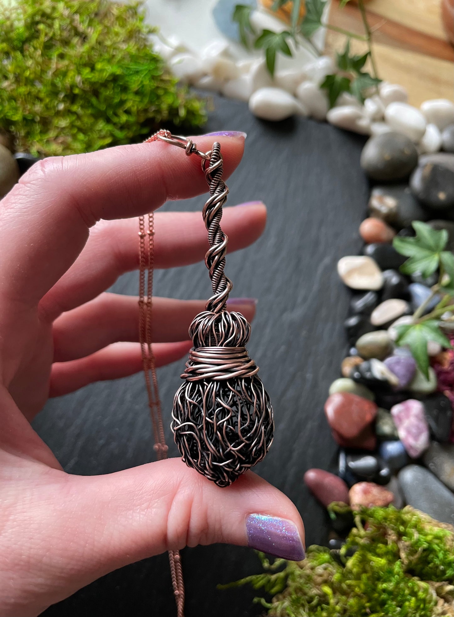 Image of an antiqued copper miniature witch broom pendant with double twisted handle