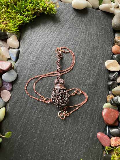 Image of an antiqued copper miniature witch broom pendant with double twisted handle