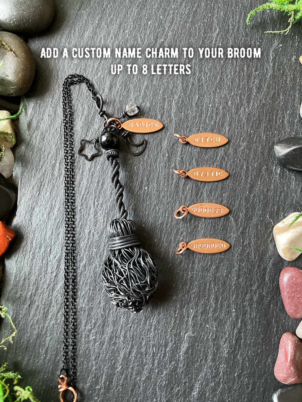 A black broom pendant, displayed on a dark slate background with decorative stones and text reading 'ADD A CUSTOM NAME CHARM TO YOUR BROOM UP TO 8 LETTERS.' Four small copper-colored name charms are shown beside it.