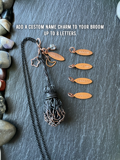 Decorative broom with customizable name charms on a stone surface