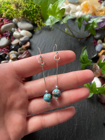 Earrings with beads on a hand against a natural background