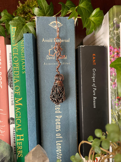 Decorative bookmark in a book on a shelf with plants in the background