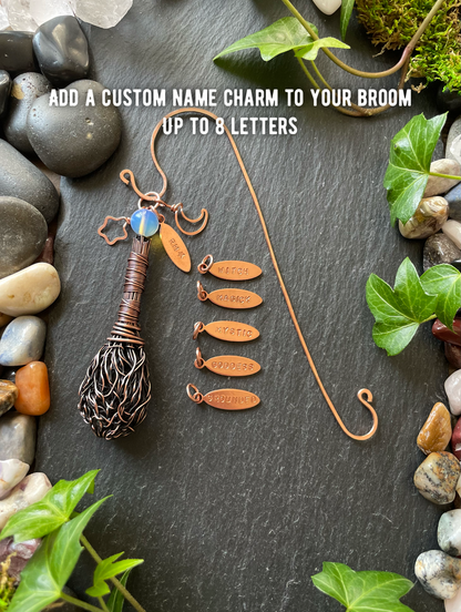 Decorative broom with customizable name charm on a stone and leaf background