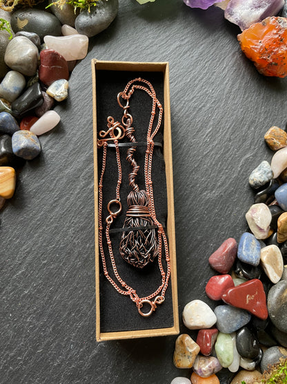 Necklace in a box surrounded by colorful stones on a dark surface
