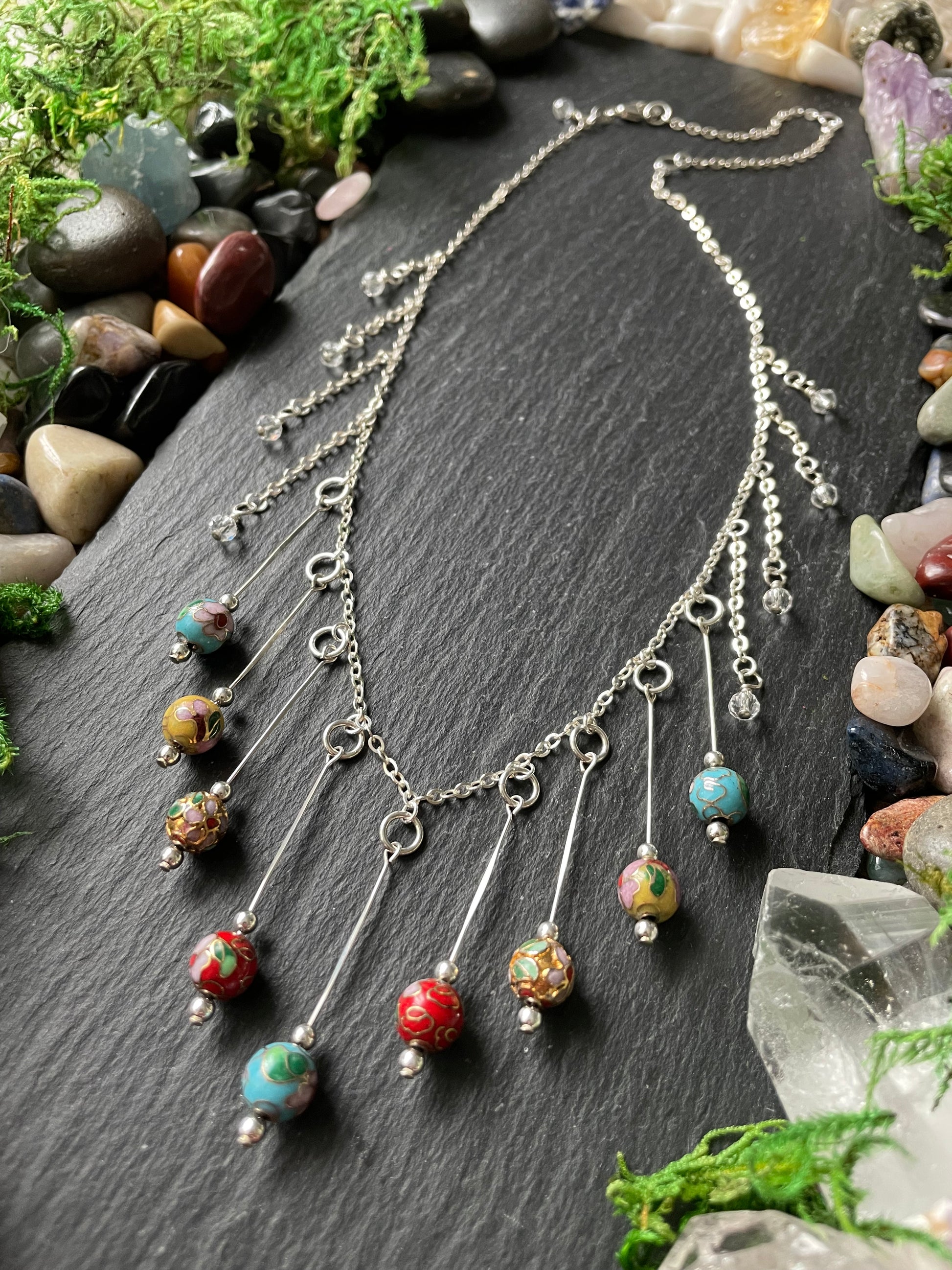 Necklace with colorful beads on a dark stone surface surrounded by stones and crystals