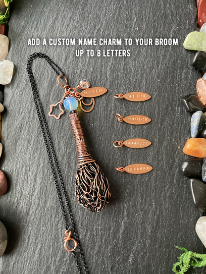 A handmade copper wire broom pendant, displayed on a dark slate background alongside five engraved copper name charms and white text that reads 'ADD A CUSTOM NAME CHARM TO YOUR BROOM UP TO 8 LETTERS'.