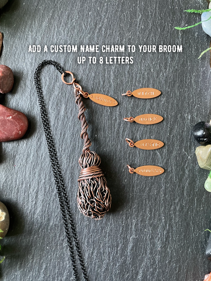 A copper-colored woven pendant necklace with a black chain is displayed on a dark slate background, alongside five small engraved copper name charms and white text that reads 'ADD A CUSTOM NAME CHARM TO YOUR BROOM UP TO 8 LETTERS'.