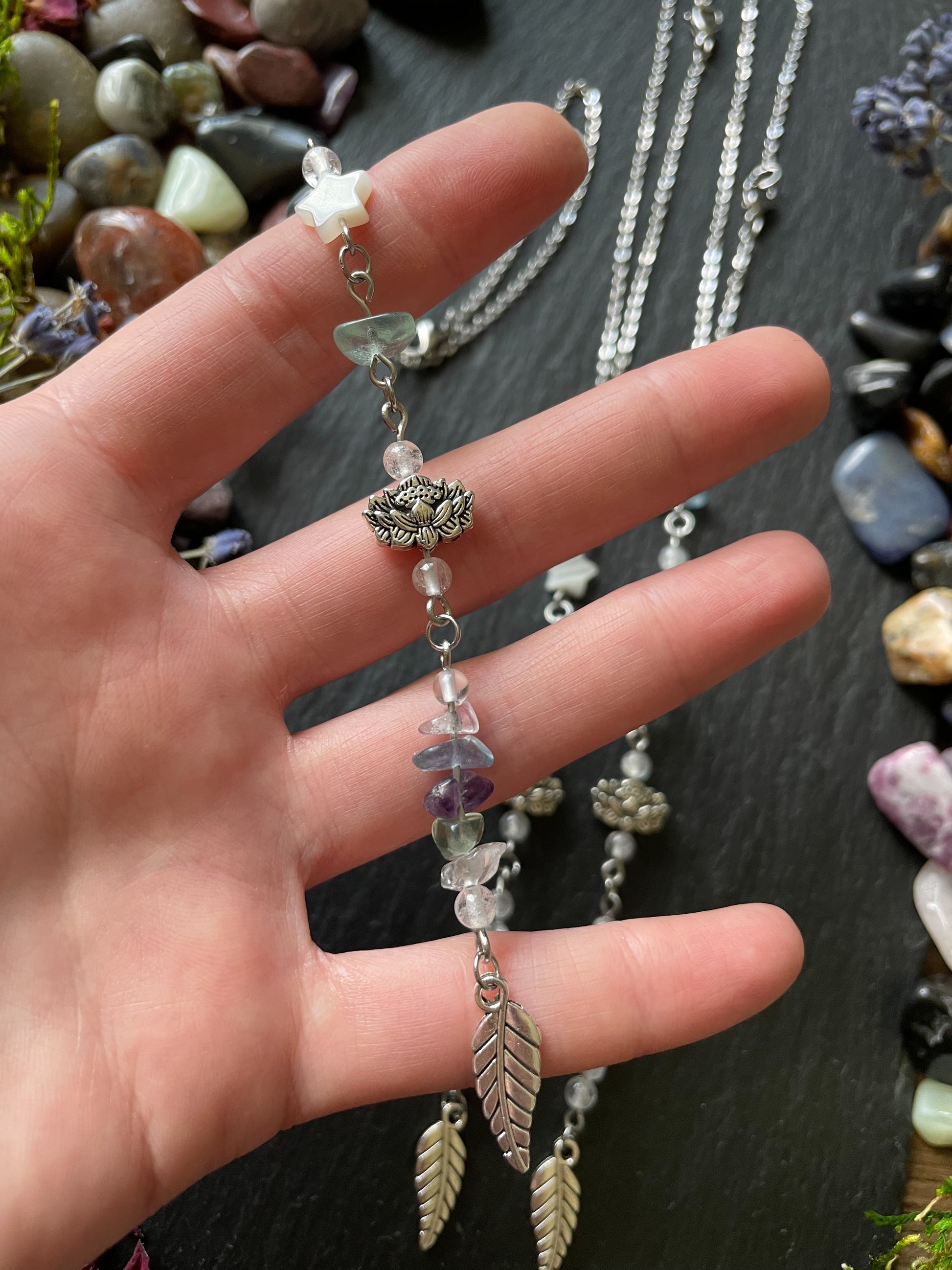 Car charm with fluorite crystal beads, lotus flower bead, and silver leaf charm displayed in hand