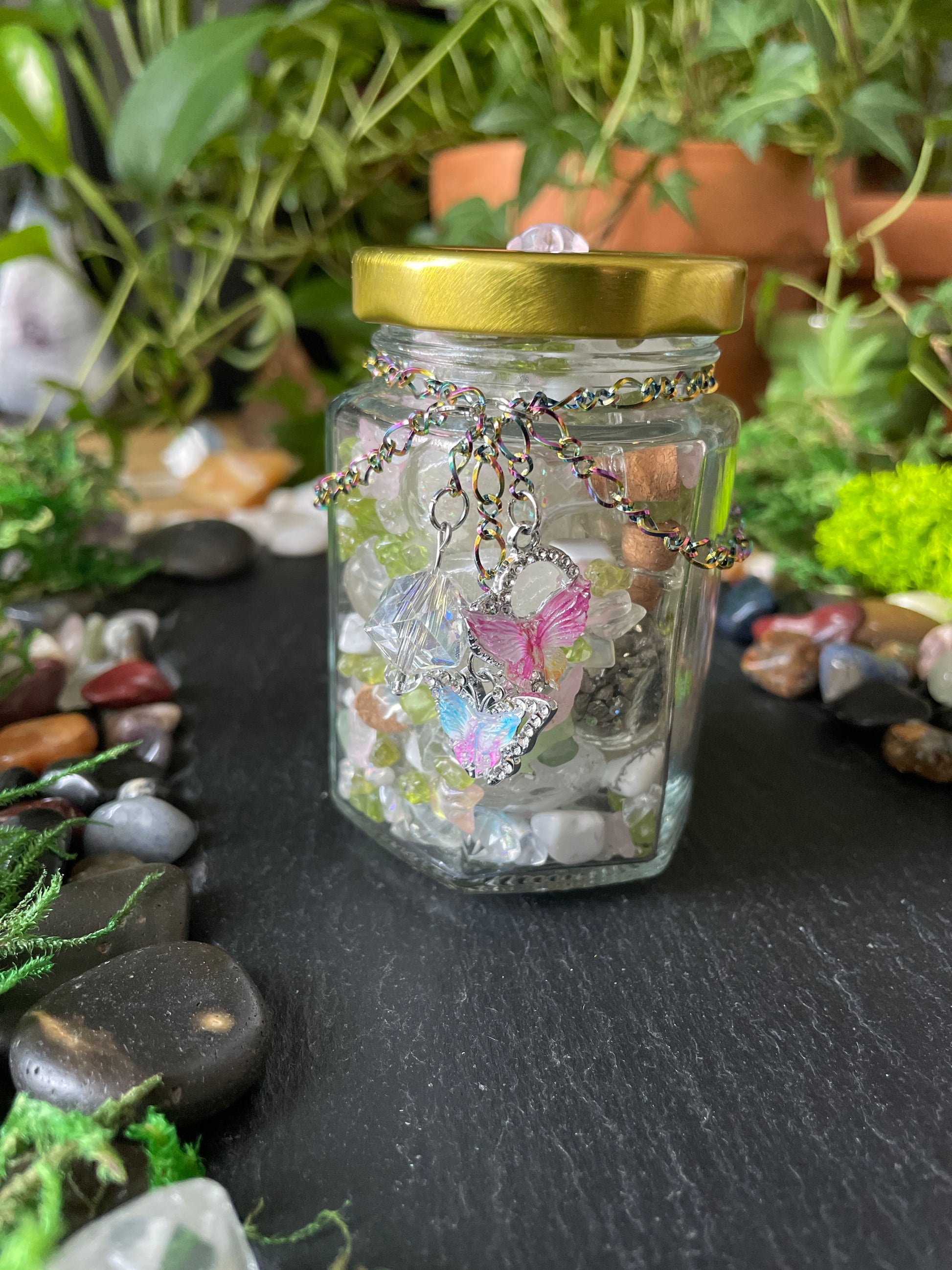 A colorful mix of gemstones in a glass jar with charms and colorful chains