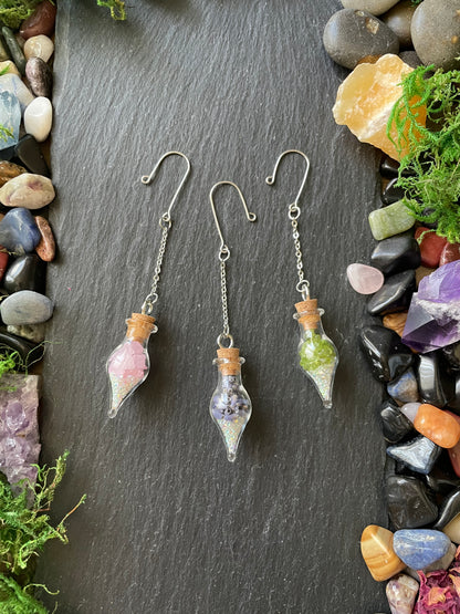 Colorful crystal plant charms on a dark slate surface with colorful stones and greenery.