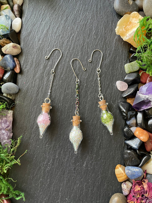 Crystal-themed plant charms on a dark stone surface with decorative stones and plants.