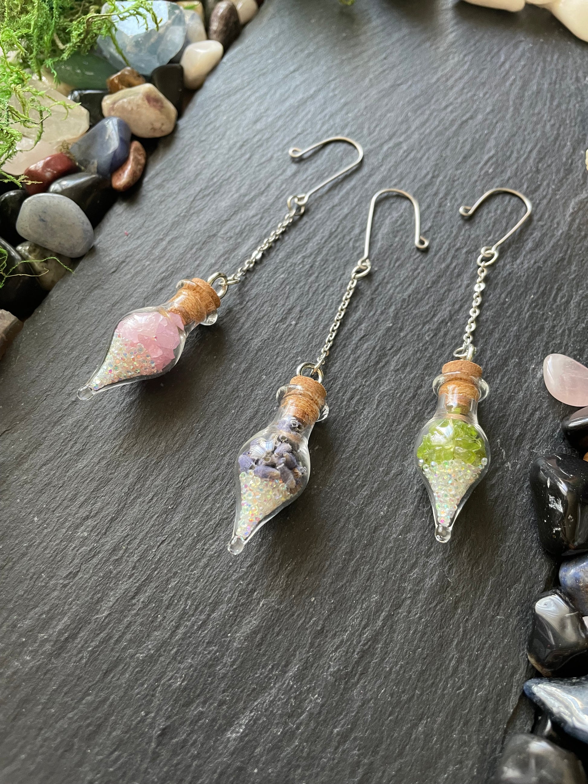 Glass bottle plant charm vials with natural elements on a stone surface