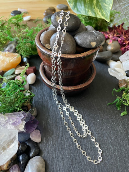 Silver chain necklace on a natural stone and crystal background
