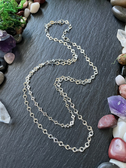 Silver chain necklace on a dark surface with stones and crystals