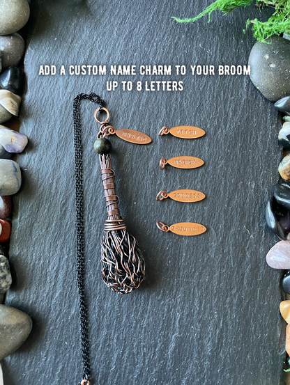 Decorative broom with customizable name charms on a stone surface