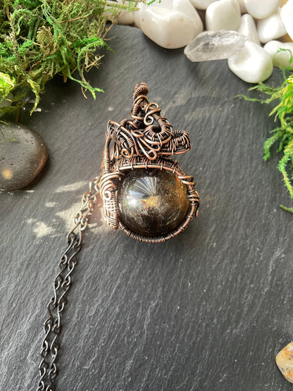 Decorative amulet with chain on a dark surface with stones and moss
