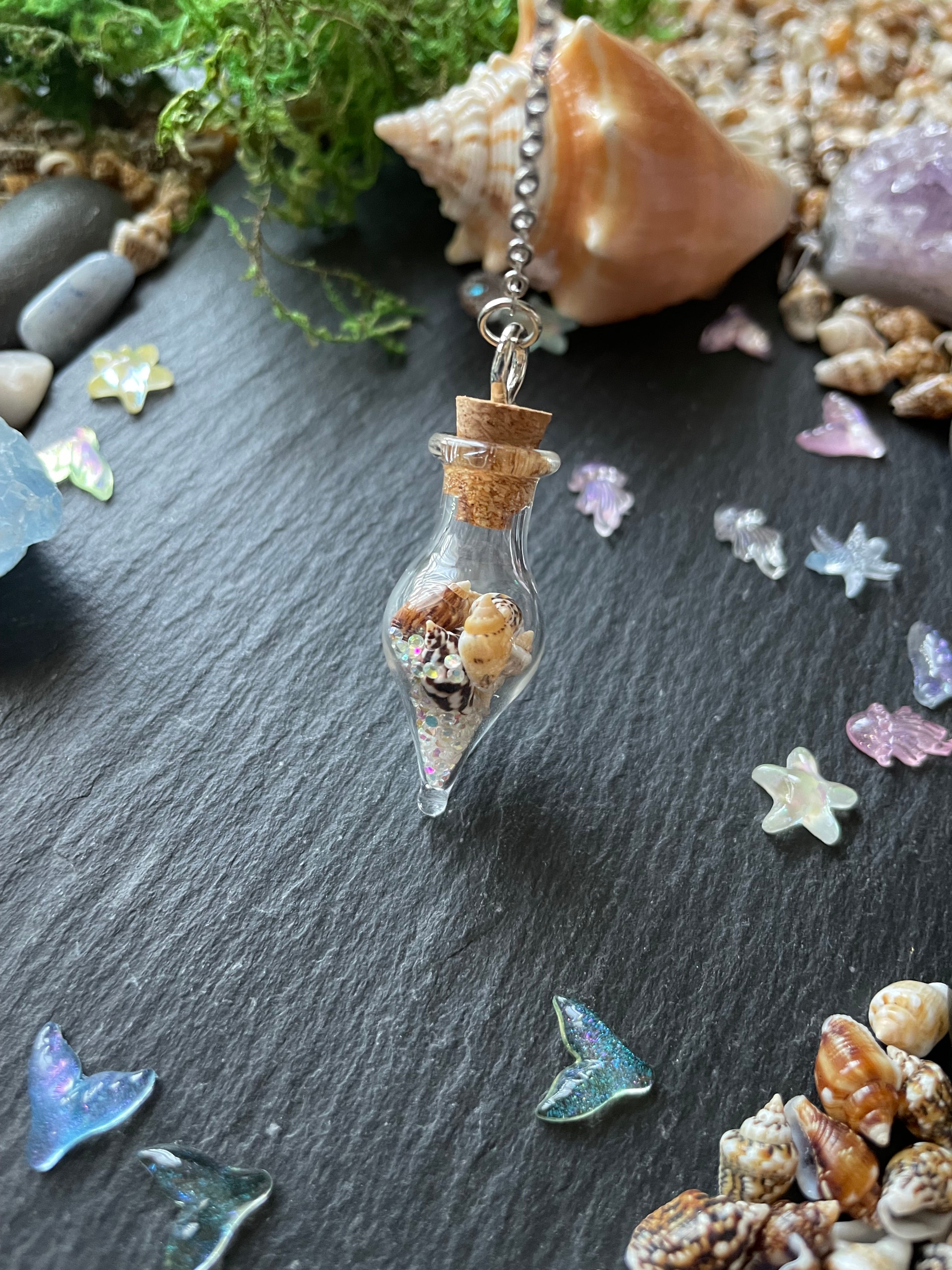 Charm with a glass bottle filled with seashells on a dark surface with seashells and starfish