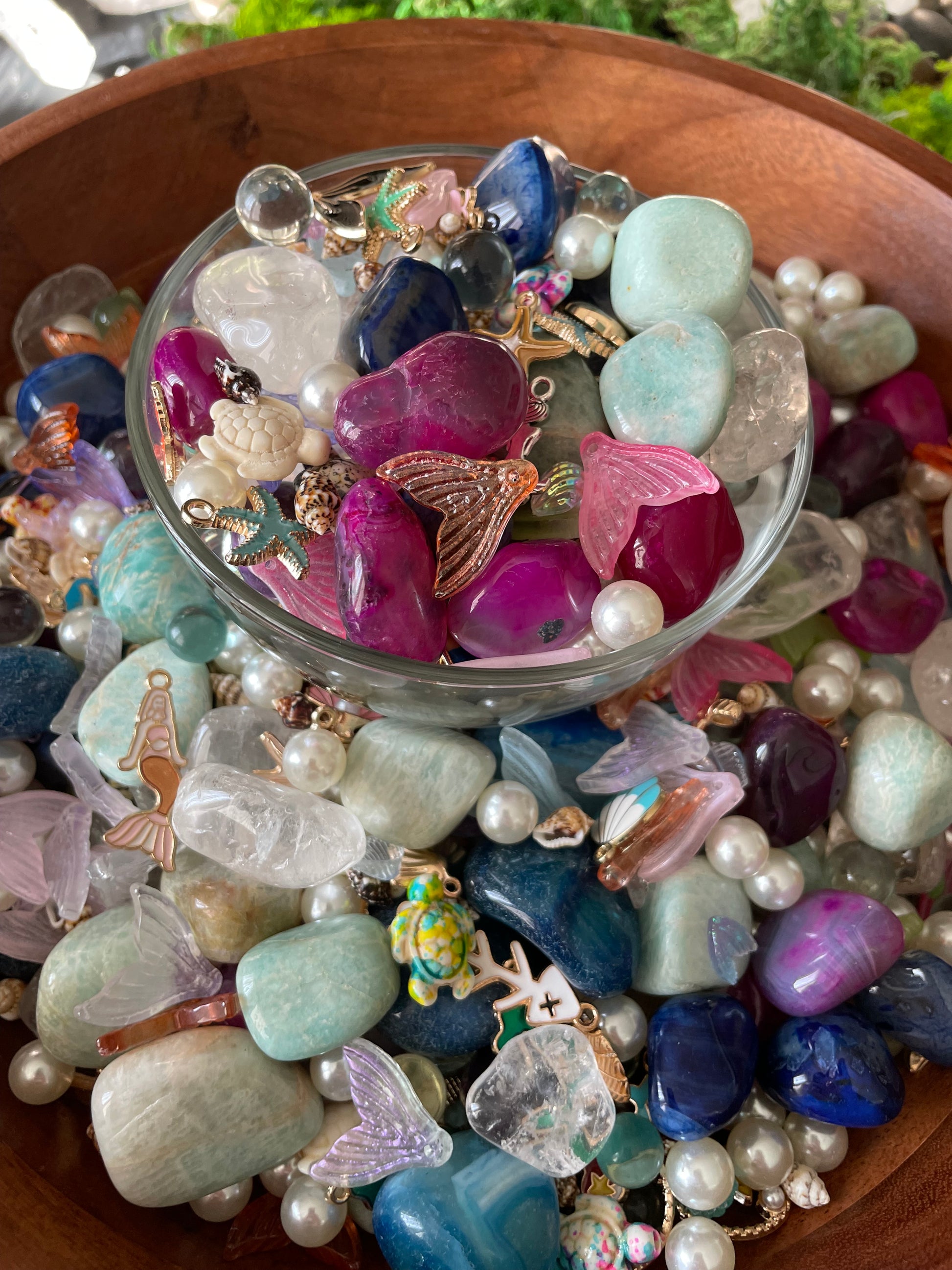 Assorted colorful stones and decorative items in a wooden bowl