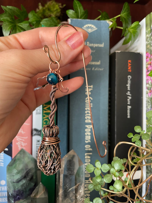 Hand holding a decorative object with books and plants in the background