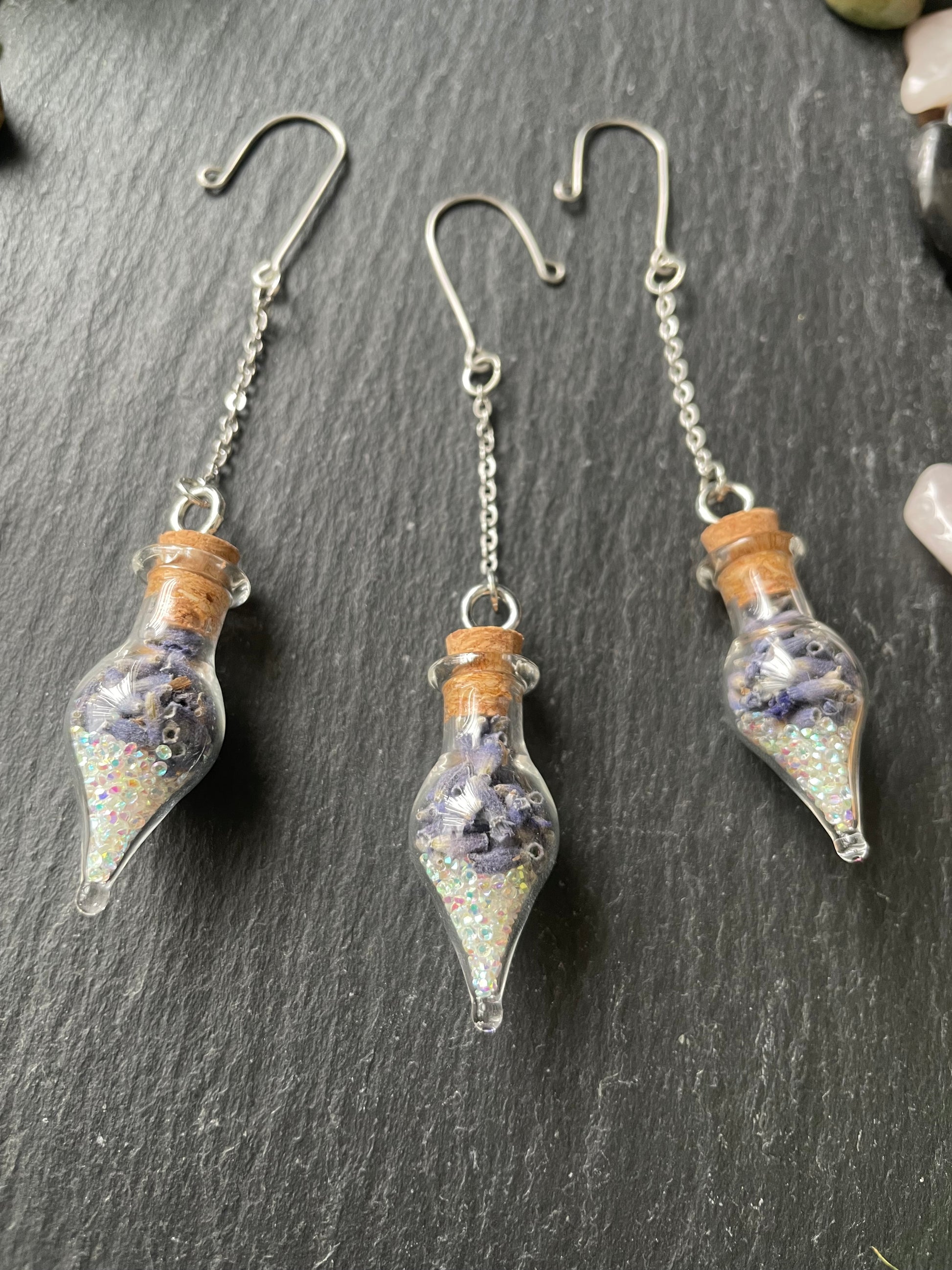 Glass vials filled with lavender and sparkles on a dark surface