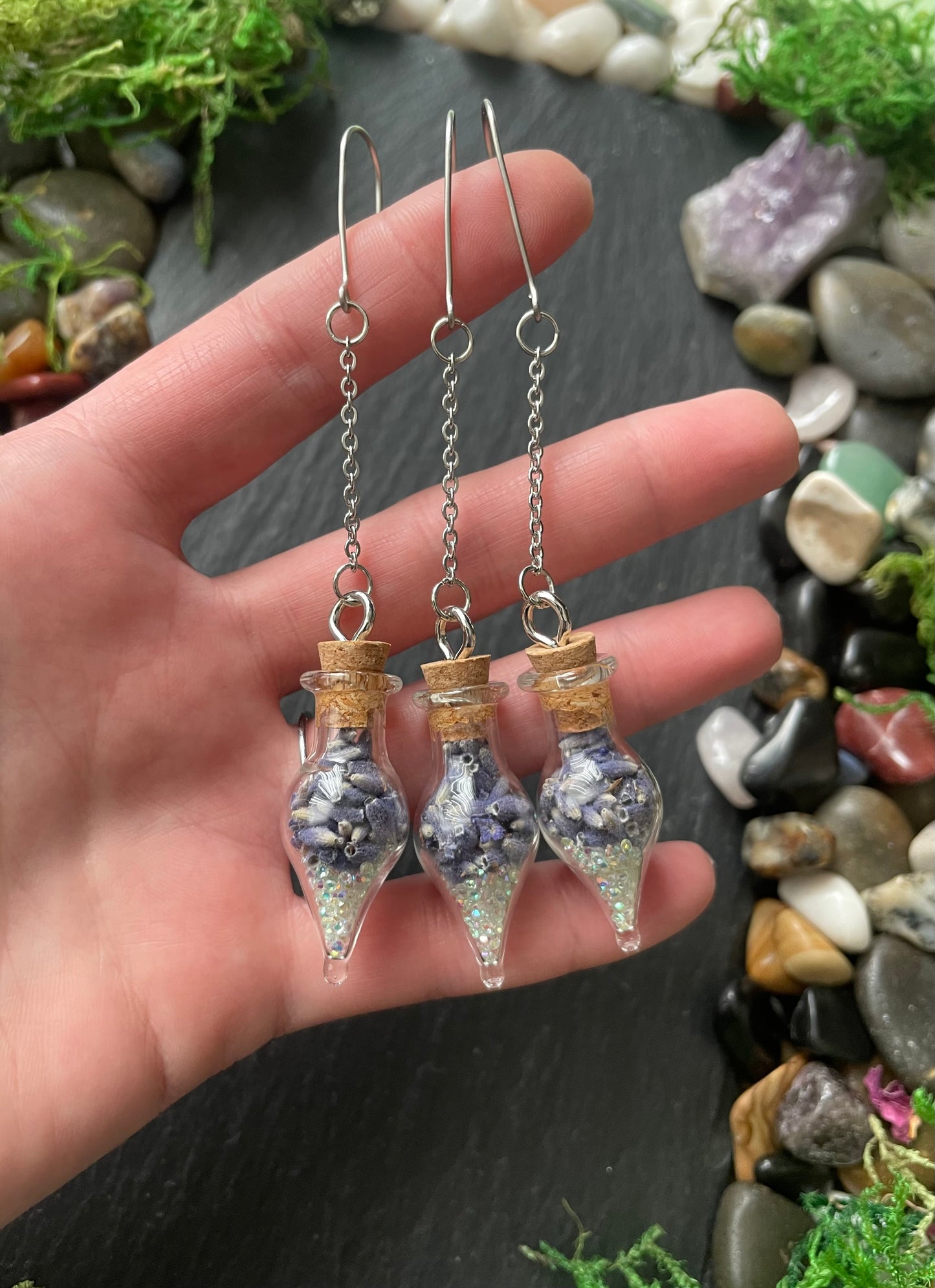 Hand holding decorative plant charms with a natural stone background