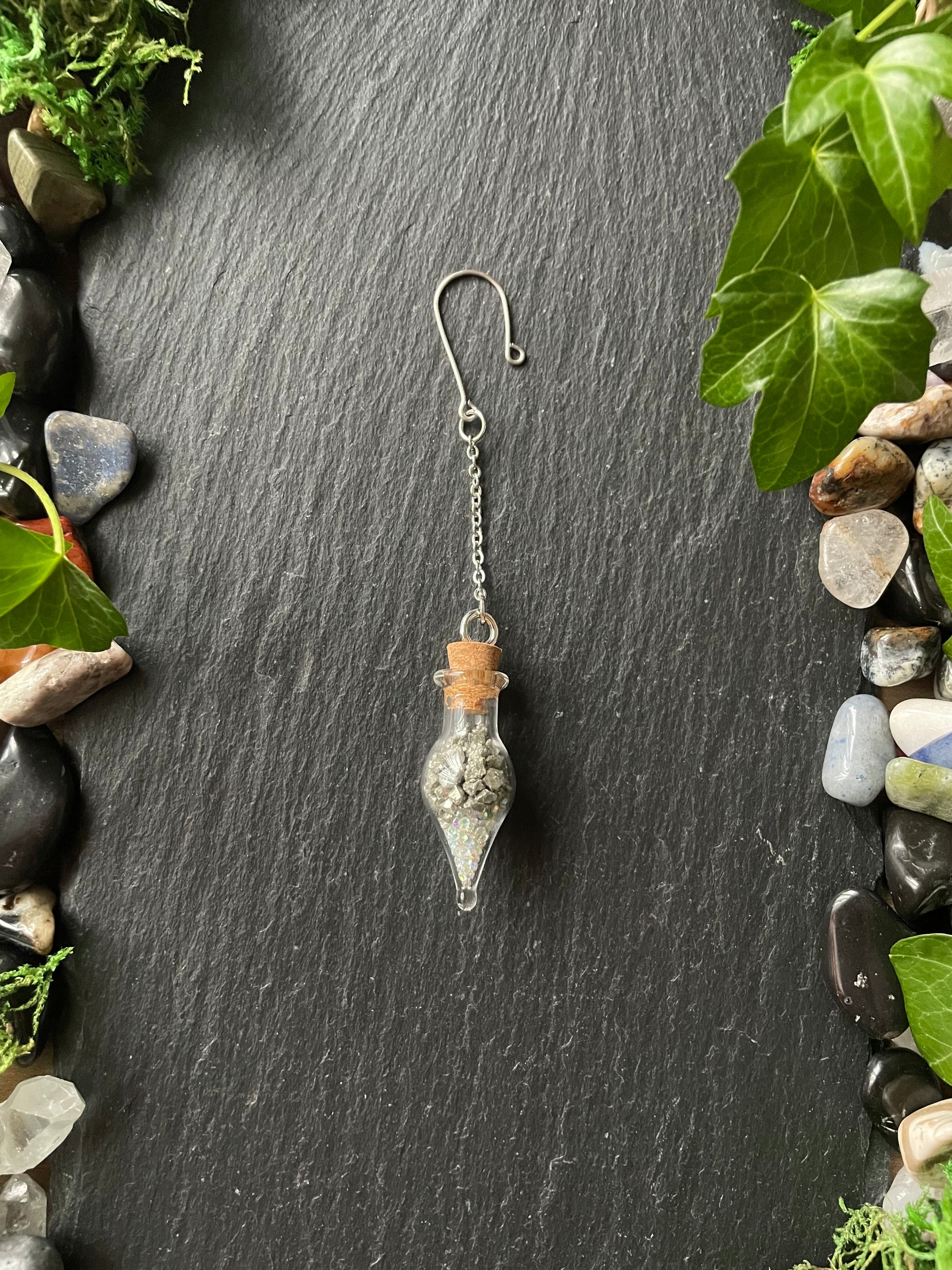 Crystal charm on a dark stone surface with greenery