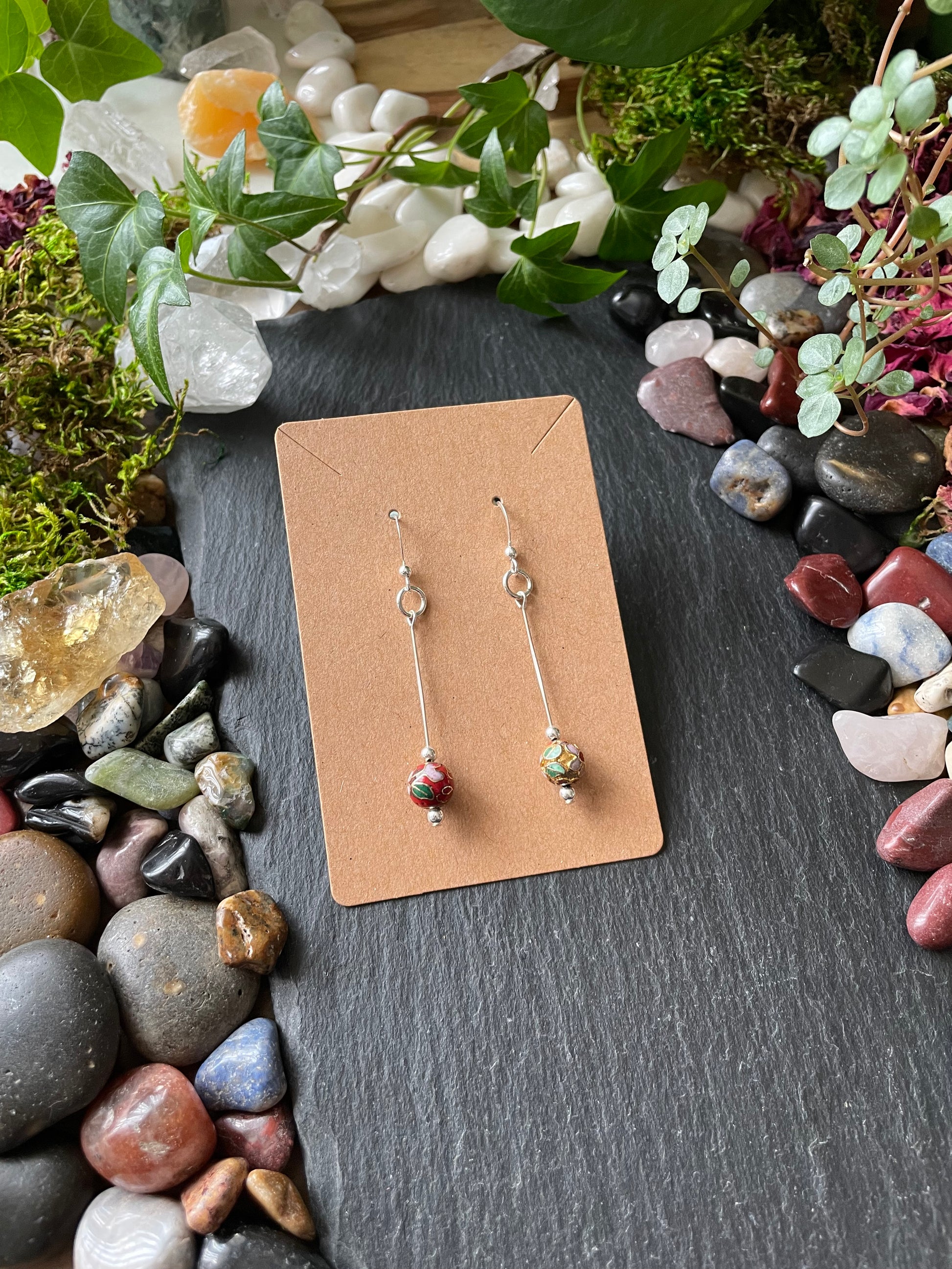 Pair of earrings on a cardboard backing with a natural stone and plant background