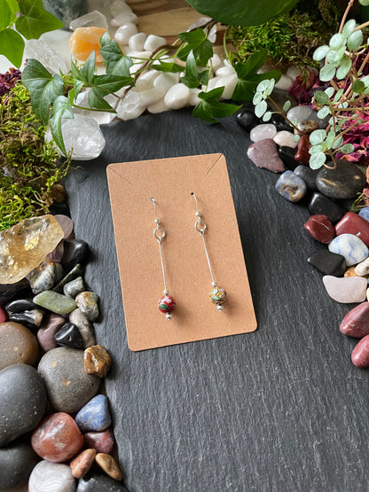 Pair of earrings on a cardboard backing with a natural stone and plant background