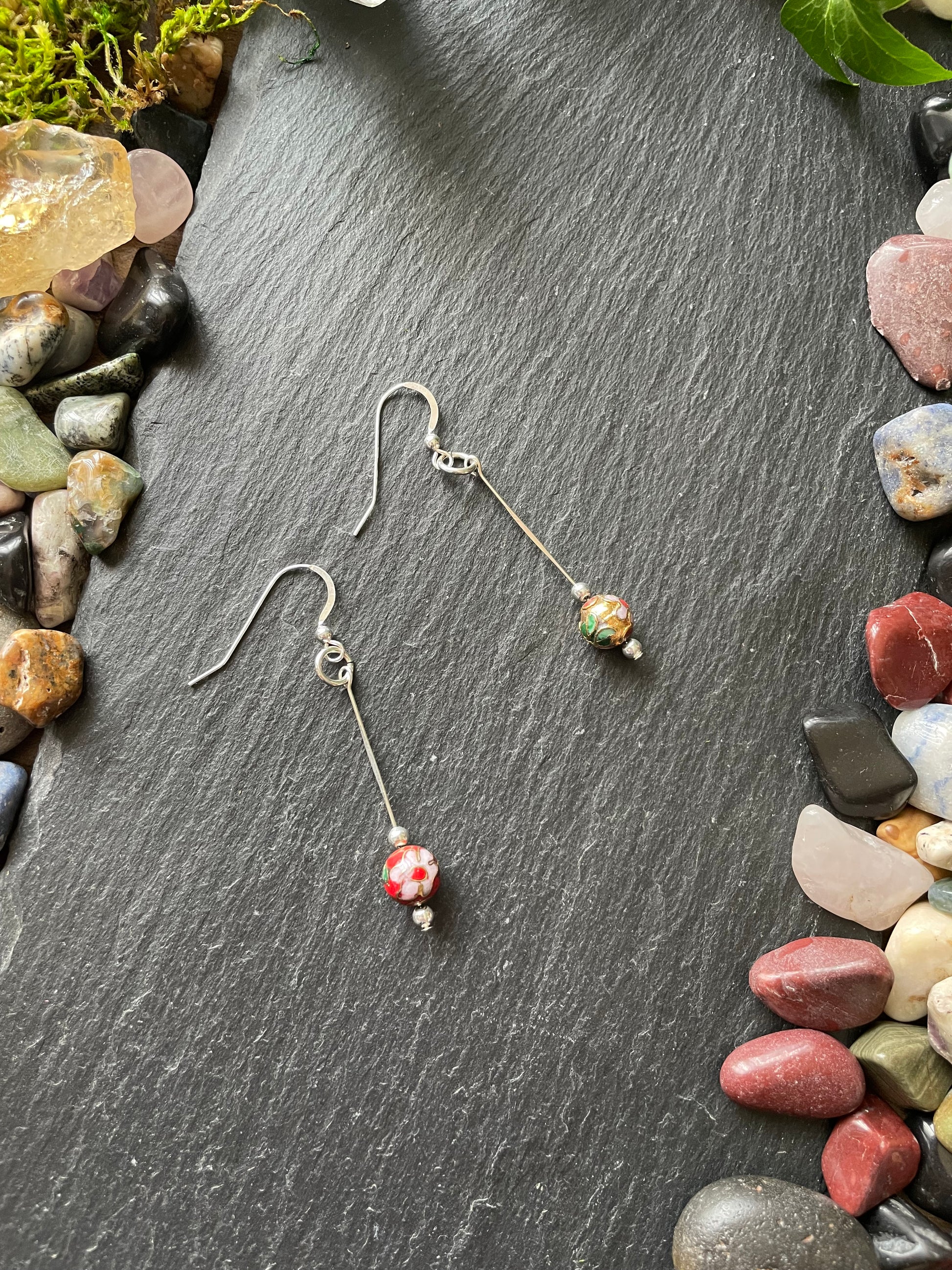 Pair of earrings with colorful beads on a dark stone surface