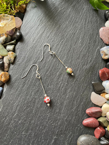 Pair of earrings with colorful beads on a dark stone surface