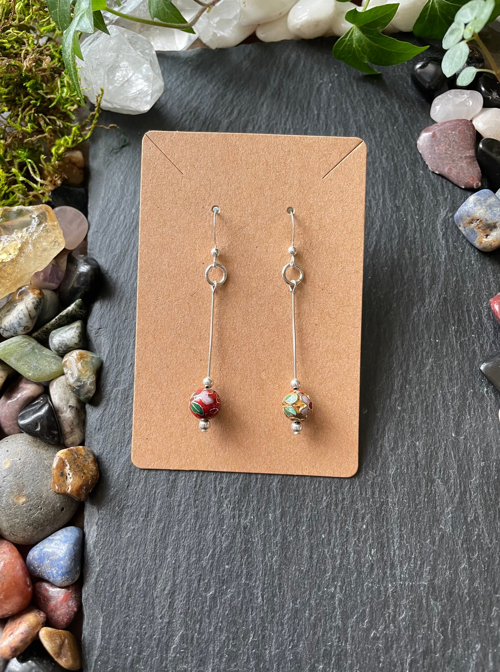 Pair of earrings on a cardboard backing with a natural stone and leaf background