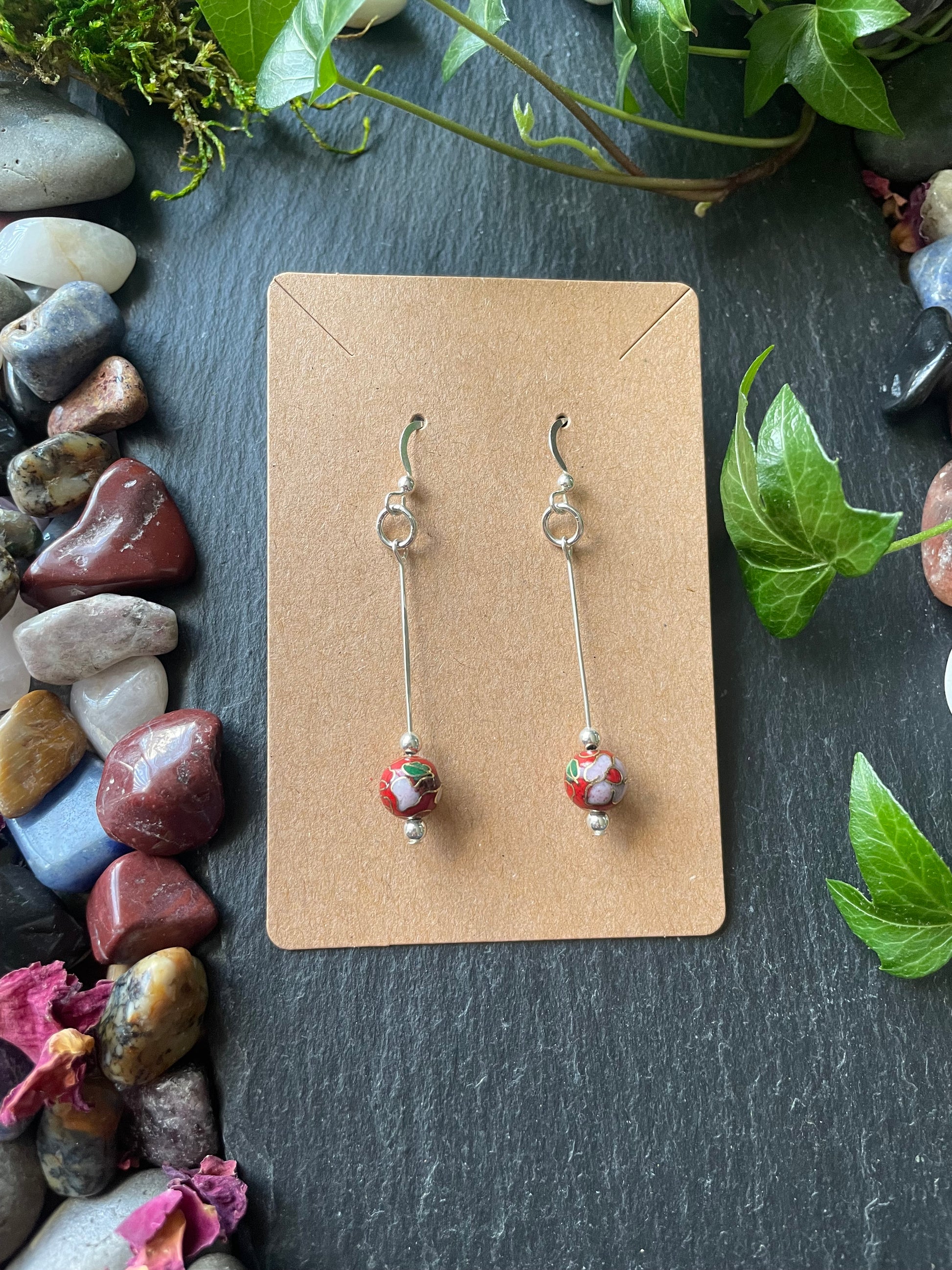 Pair of earrings on a cardboard backing with a natural stone and leaf background