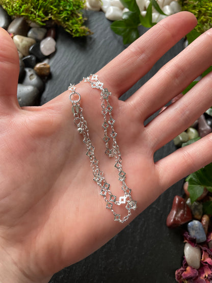 Silver chain bracelet on a hand with a natural stone background