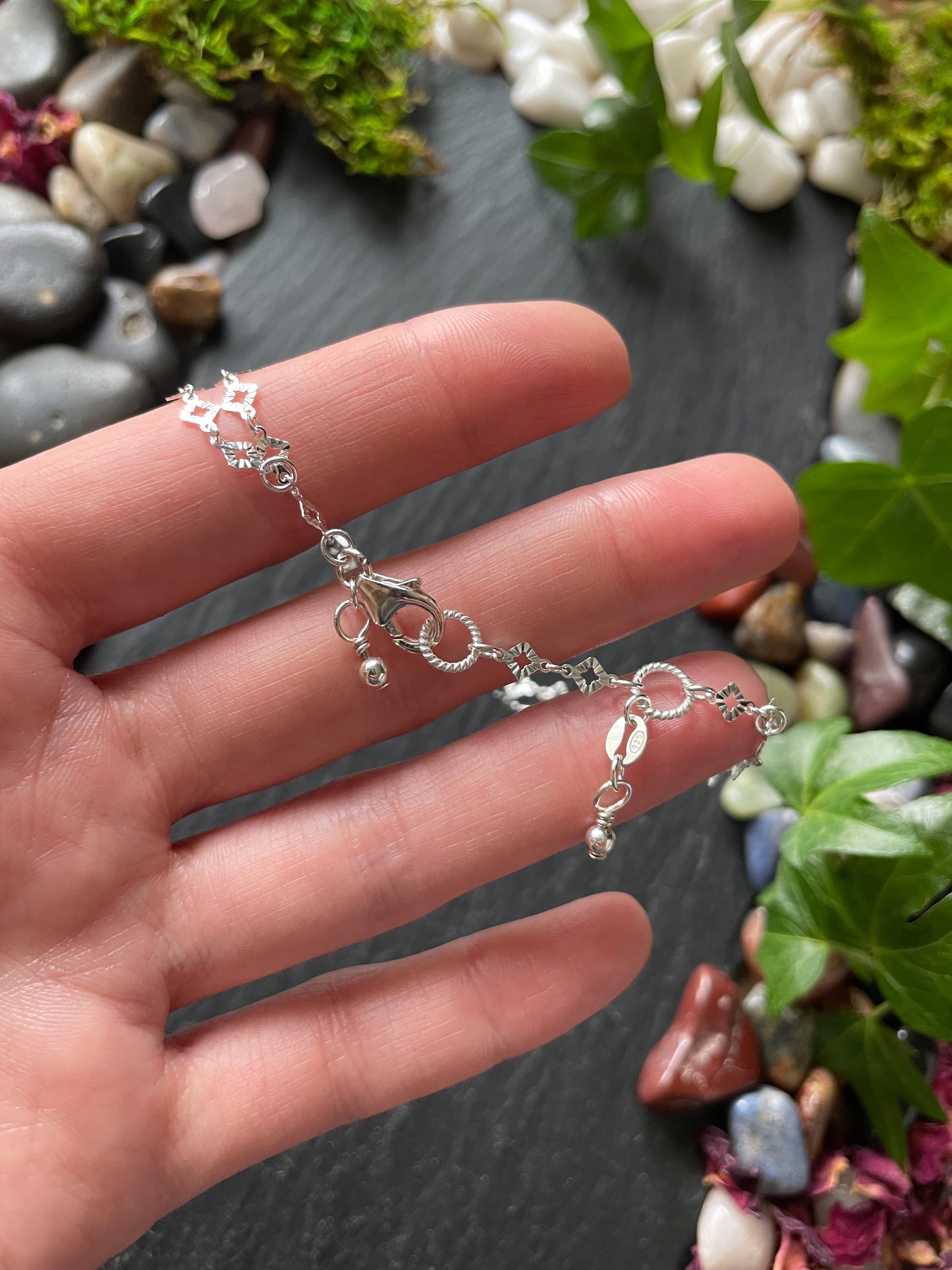 Silver bracelet on a hand with a natural background of stones and plants