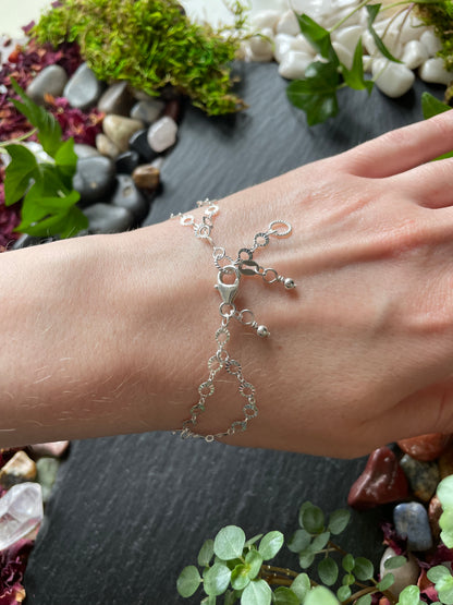 Silver bracelet on a wrist with a natural stone and plant background