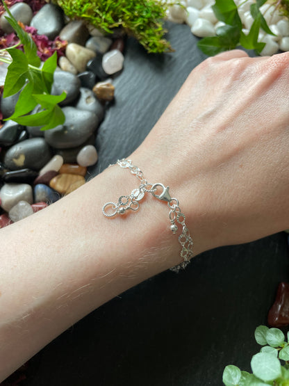 Silver bracelet on a wrist with a natural background of stones and plants