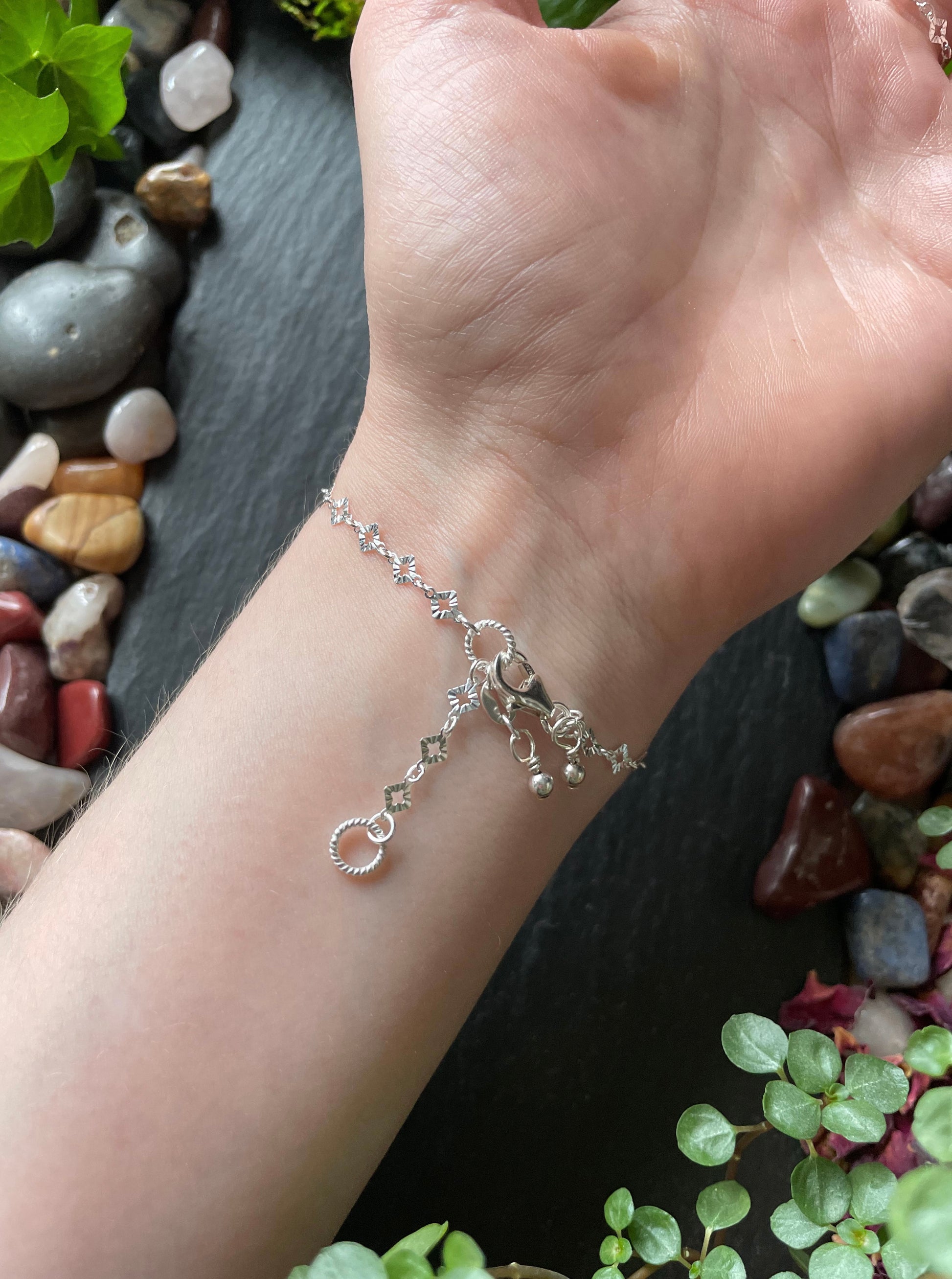 Silver bracelet on a wrist with a natural stone and plant background