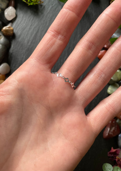 Hand wearing a delicate ring with a blurred natural background