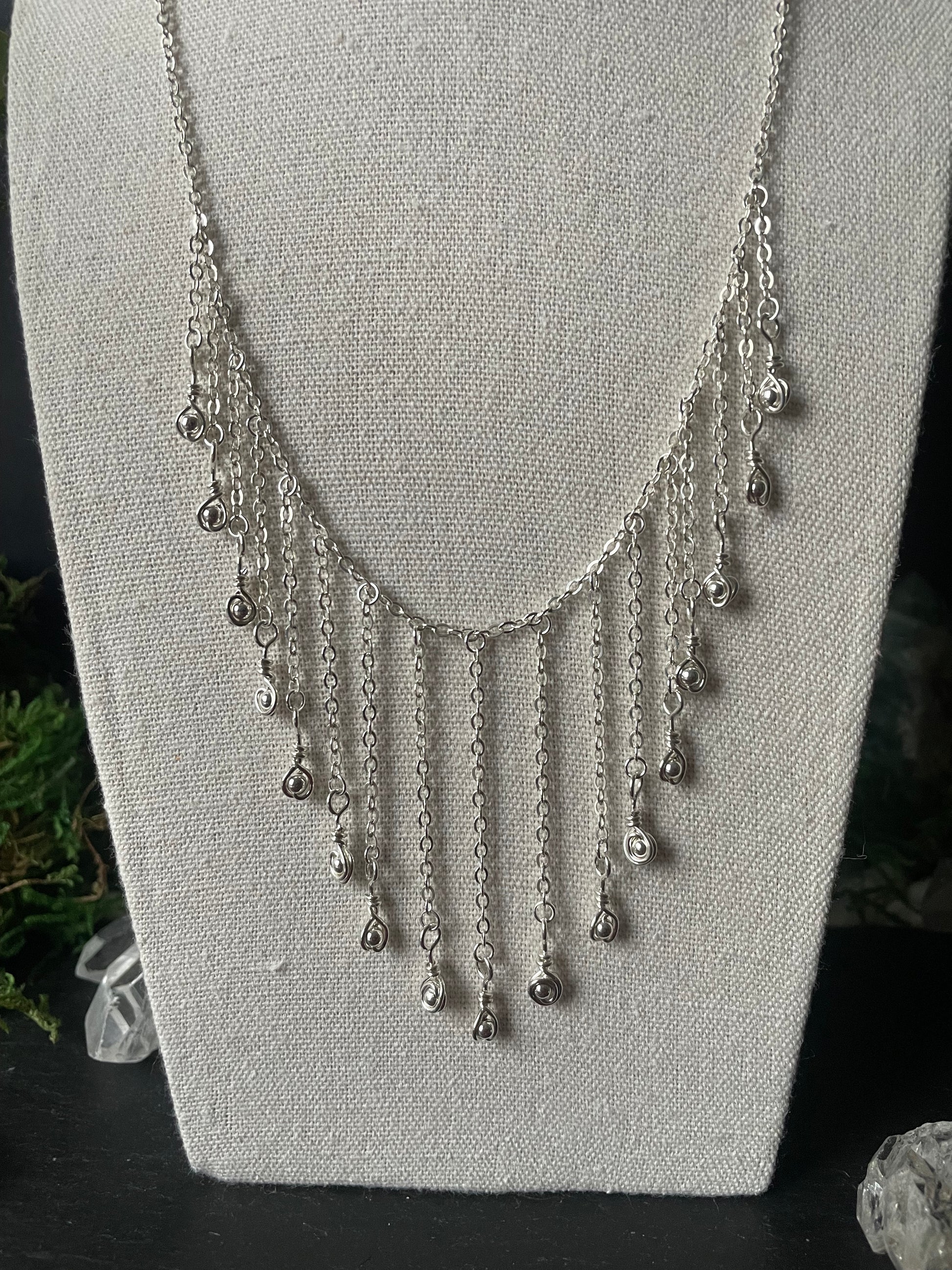 Close-up of an elegant necklace with hanging chain and silver charms
