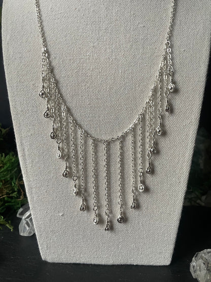 Close-up of an elegant necklace with hanging chain and silver charms