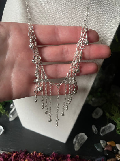 Silver chain necklace on a hand with a blurred background